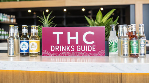 a modern bar with various glass bottles and a large pink sign reading 'THC Drinks Guide'