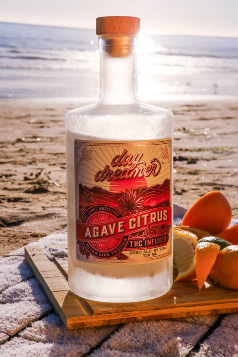 Bottle of agave citrus THC mixer with a beach background
